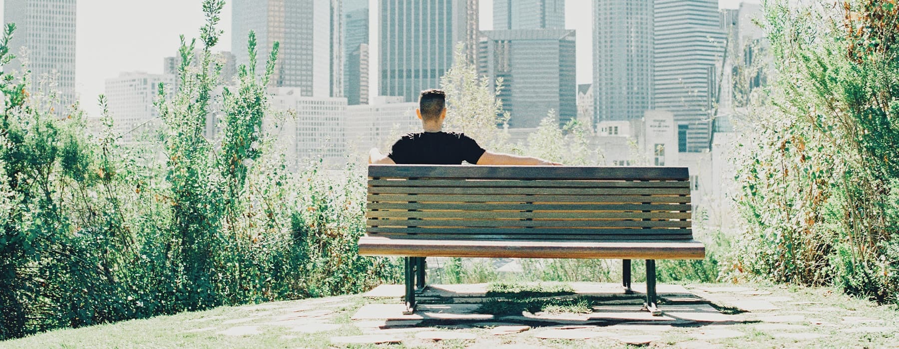 lifestyle image of a person sitting on a bench with city views